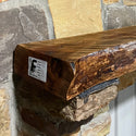 Solid live edge cherry fireplace mantel mounted on a stone wall.