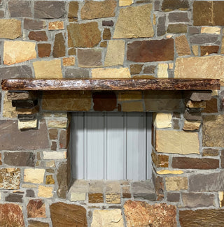 Solid live edge cherry fireplace mantel mounted on a stone wall.