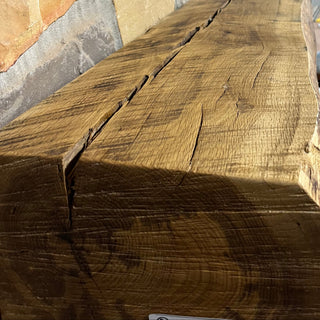 Solid live edge oak fireplace mantel mounted on a stone wall.