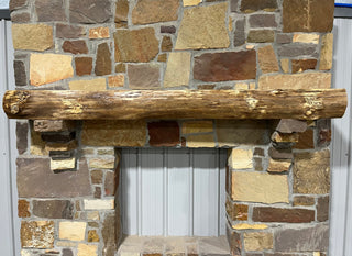 Solid live edge oak fireplace mantel mounted on a stone wall.