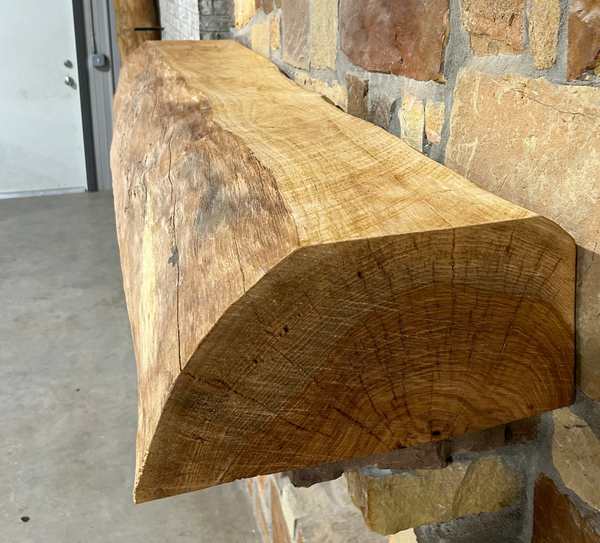 Solid live edge pecan fireplace mantel mounted on a stone wall.