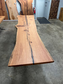 Live edge red oak wood slab with rich grain patterns, natural knots, and kiln-dried hardwood surface for custom furniture or table making.