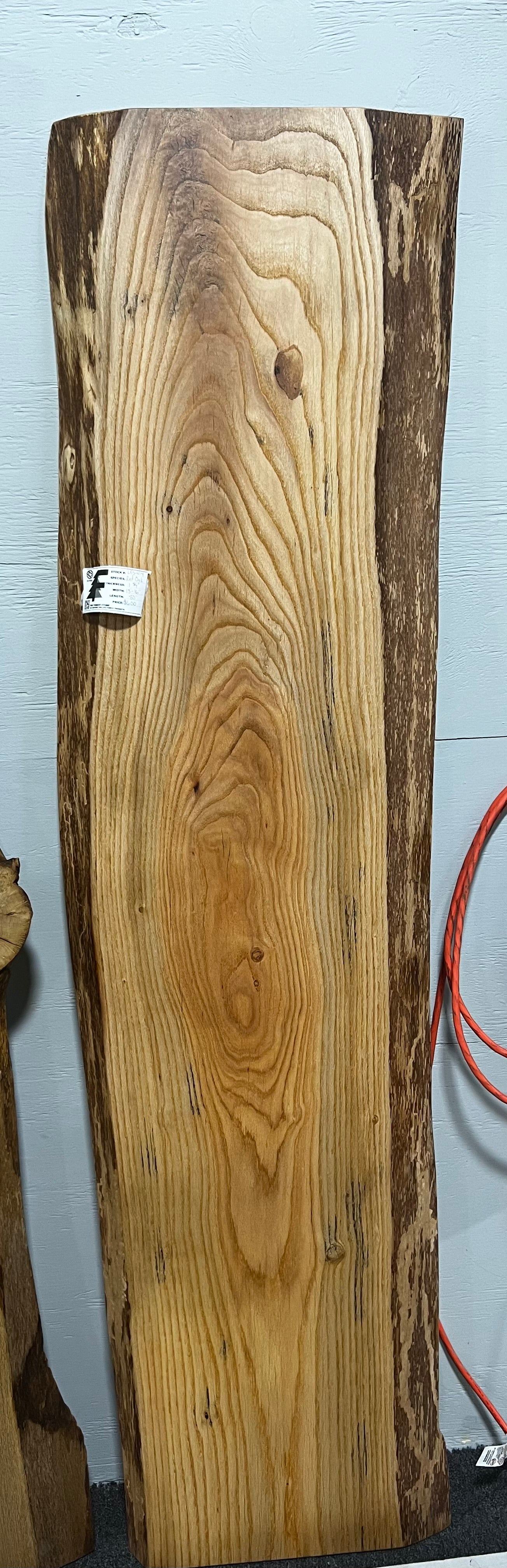 Live edge red oak wood slab with rich grain patterns, natural knots, and kiln-dried hardwood surface for custom furniture or table making.