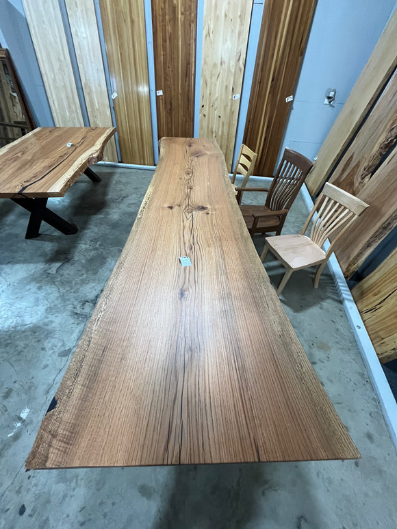 Live edge red oak wood slab with rich grain patterns, natural knots, and kiln-dried hardwood surface for custom furniture or table making.