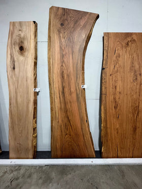 Live edge red oak wood slab with rich grain patterns, natural knots, and kiln-dried hardwood surface for custom furniture or table making.