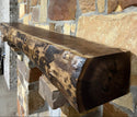 Solid live edge walnut fireplace mantel mounted on a stone wall.