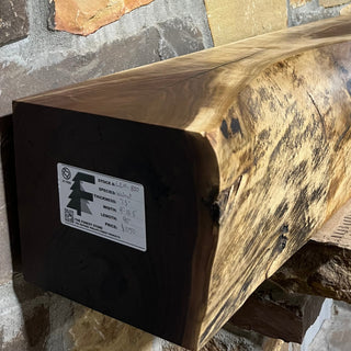 Solid live edge walnut fireplace mantel mounted on a stone wall.