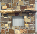 Solid live edge walnut fireplace mantel mounted on a stone wall.