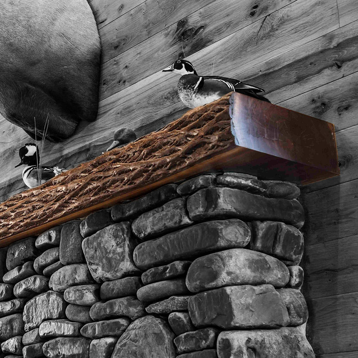 a walnut tree cut with the bark showing on a rock fireplace. 