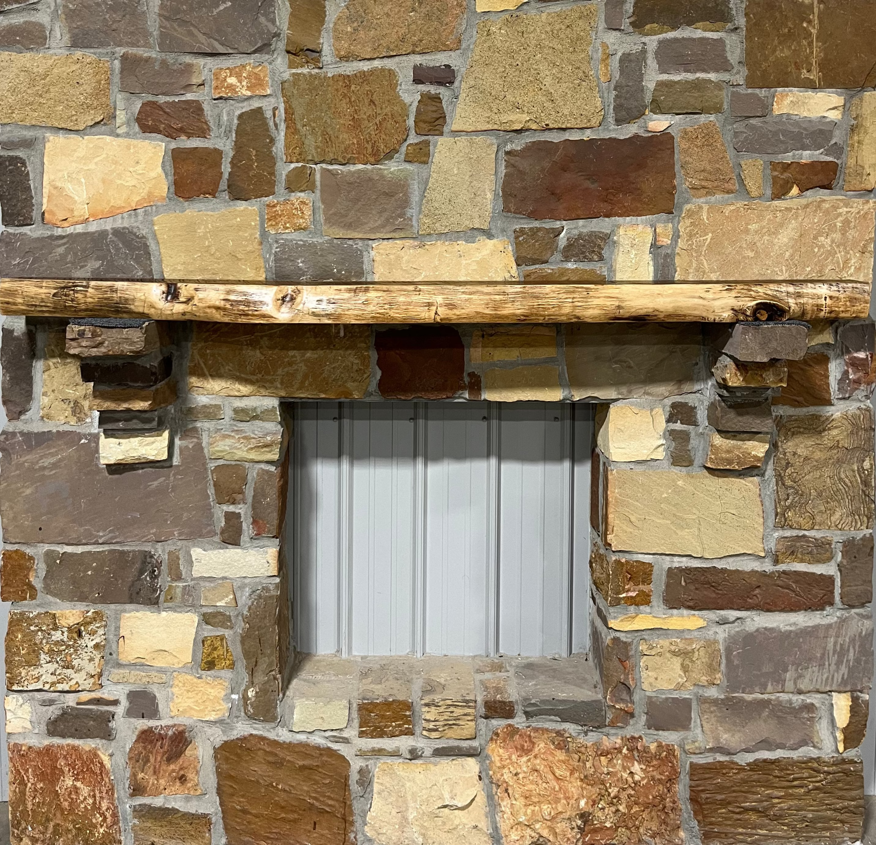 A solid walnut wood fireplace mantel with the side of the tree exposed on a stone wall.