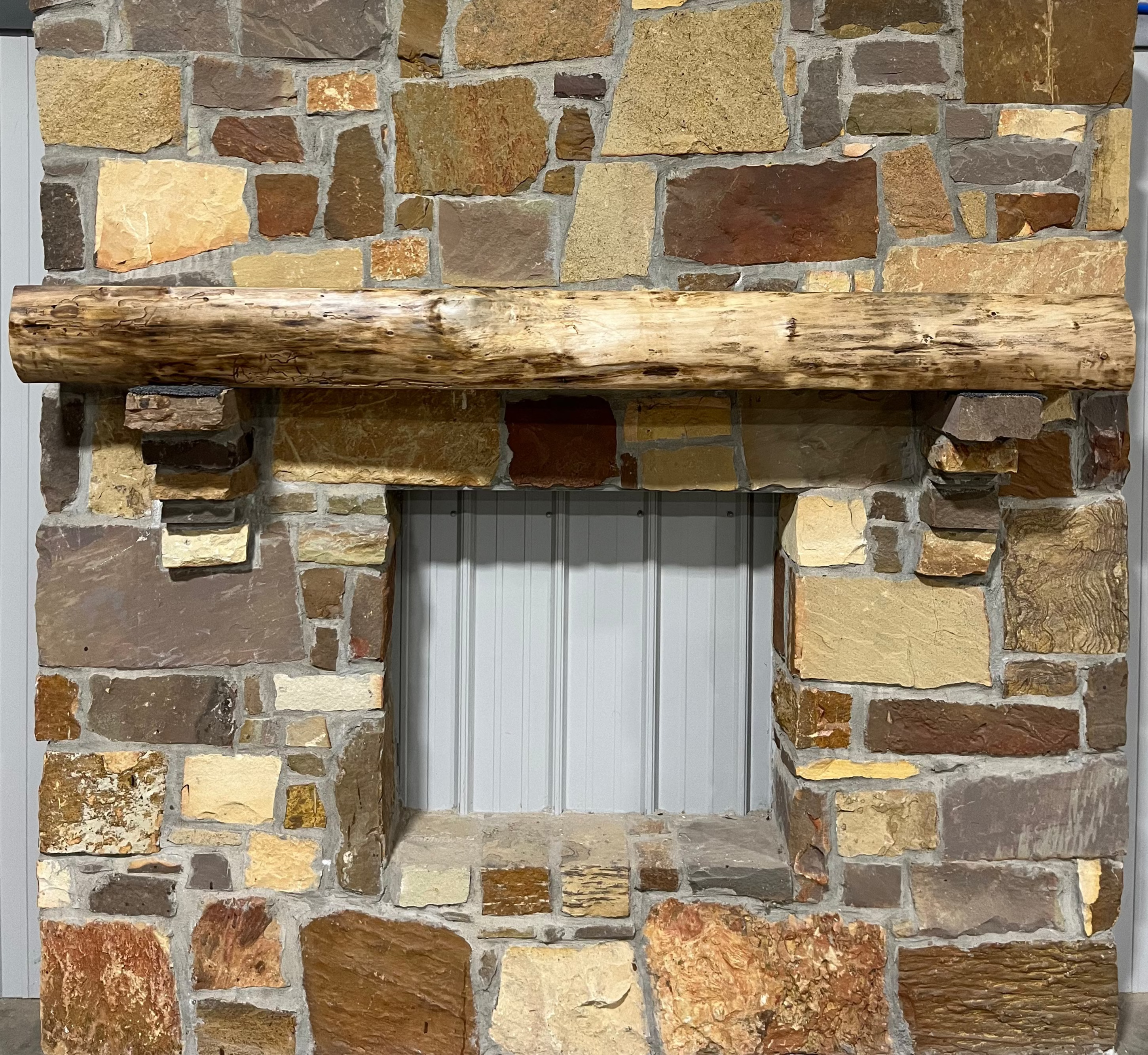 A solid walnut wood fireplace mantel with the side of the tree exposed on a stone wall.