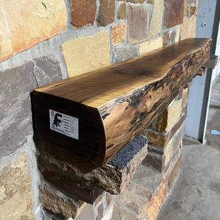 A solid walnut wood fireplace mantel with the side of the tree exposed. 