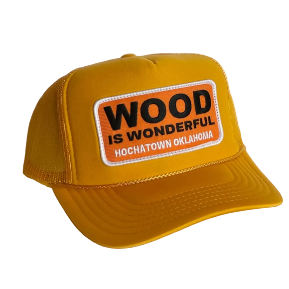 A mustard yellow trucker hat with a Wood is Wonderful Hochatown Oklahoma patch