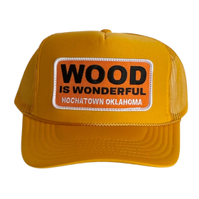 A mustard yellow trucker hat with a Wood is Wonderful Hochatown Oklahoma patch
