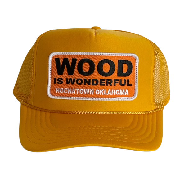 A mustard yellow trucker hat with a Wood is Wonderful Hochatown Oklahoma patch