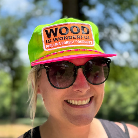 Person wearing a neon green and pink cap with 'Wood is Wonderful' Phillips Forest Products patch