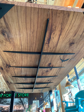 Pecan Spine Table side view with golden-brown wood, black resin cracks, and steel braces.