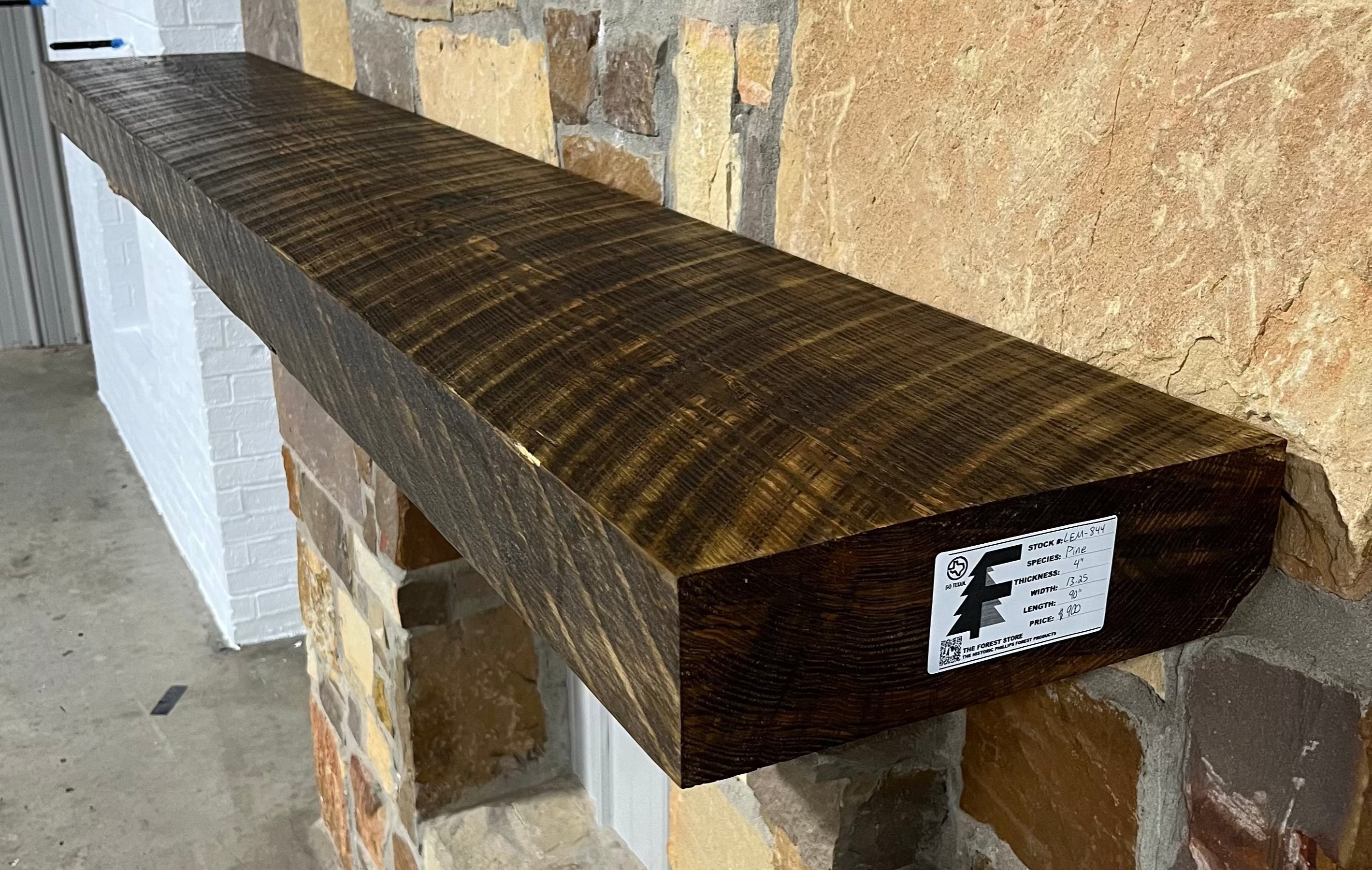 Solid pine beam fireplace mantel mounted on a stone wall.