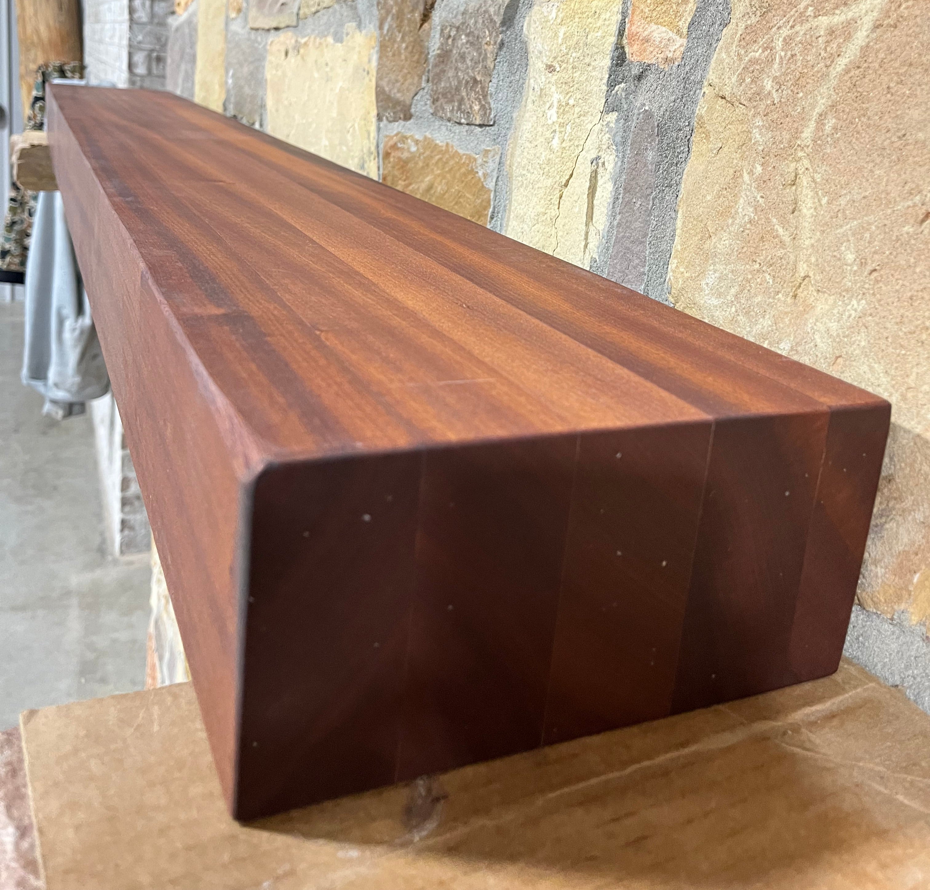 solid sapele beam fireplace mantel mounted on a stone wall