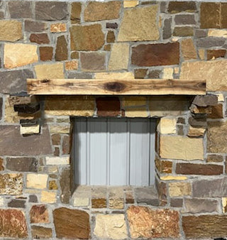 walnut beam fireplace mantel on a stone wall