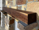 Solid walnut beam fireplace mantel with mounted on a stone fireplace wall.