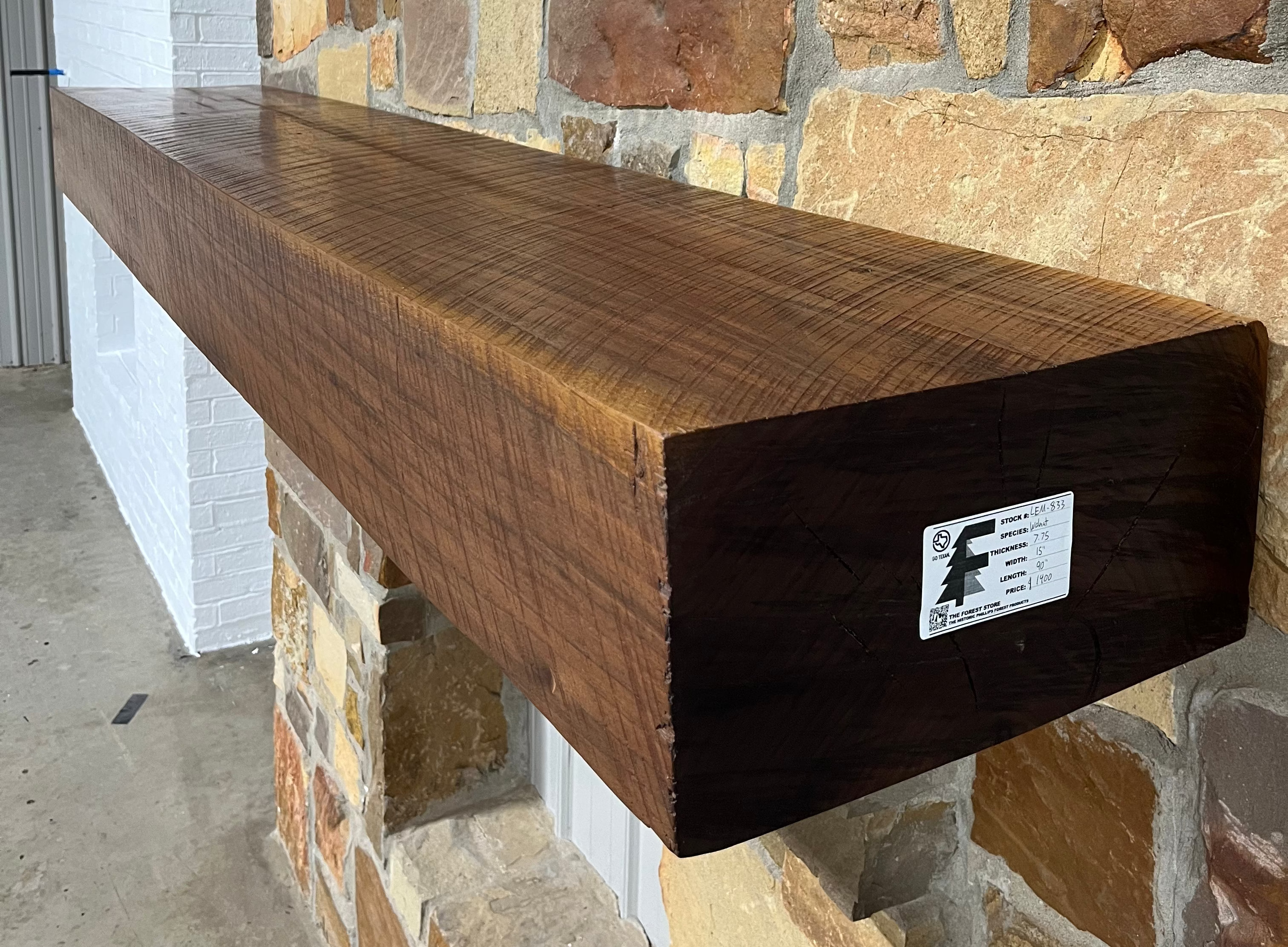 Solid walnut beam fireplace mantel with mounted on a stone fireplace wall.