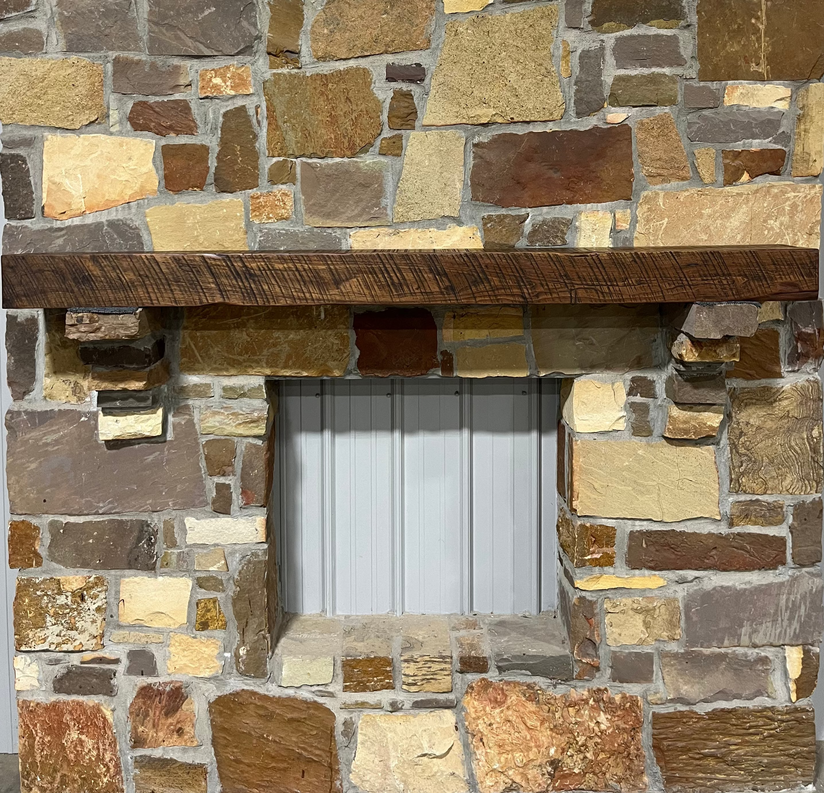 Solid walnut beam fireplace mantel with mounted on a stone fireplace wall.