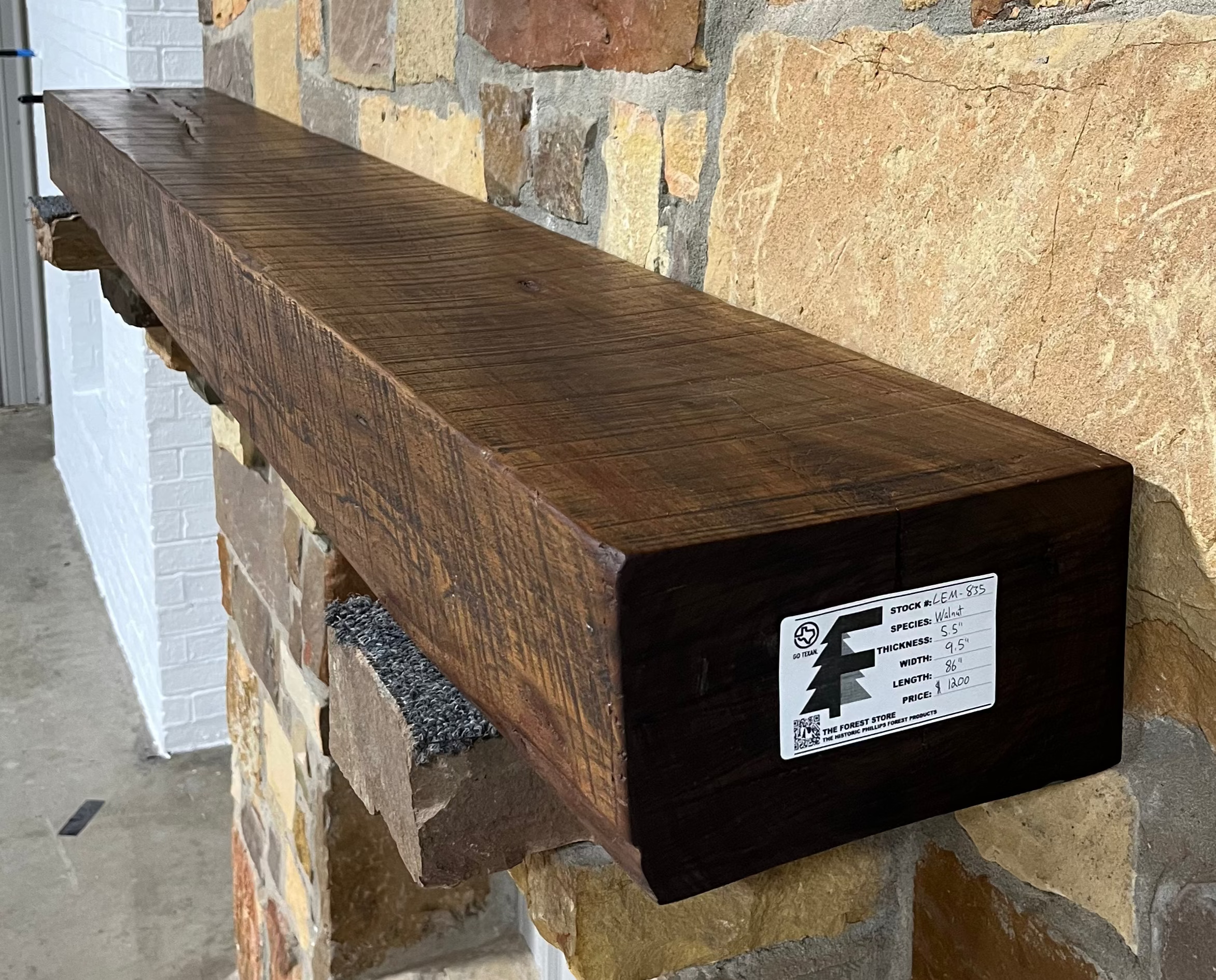 Solid walnut beam fireplace mantel with mounted on a stone fireplace wall.