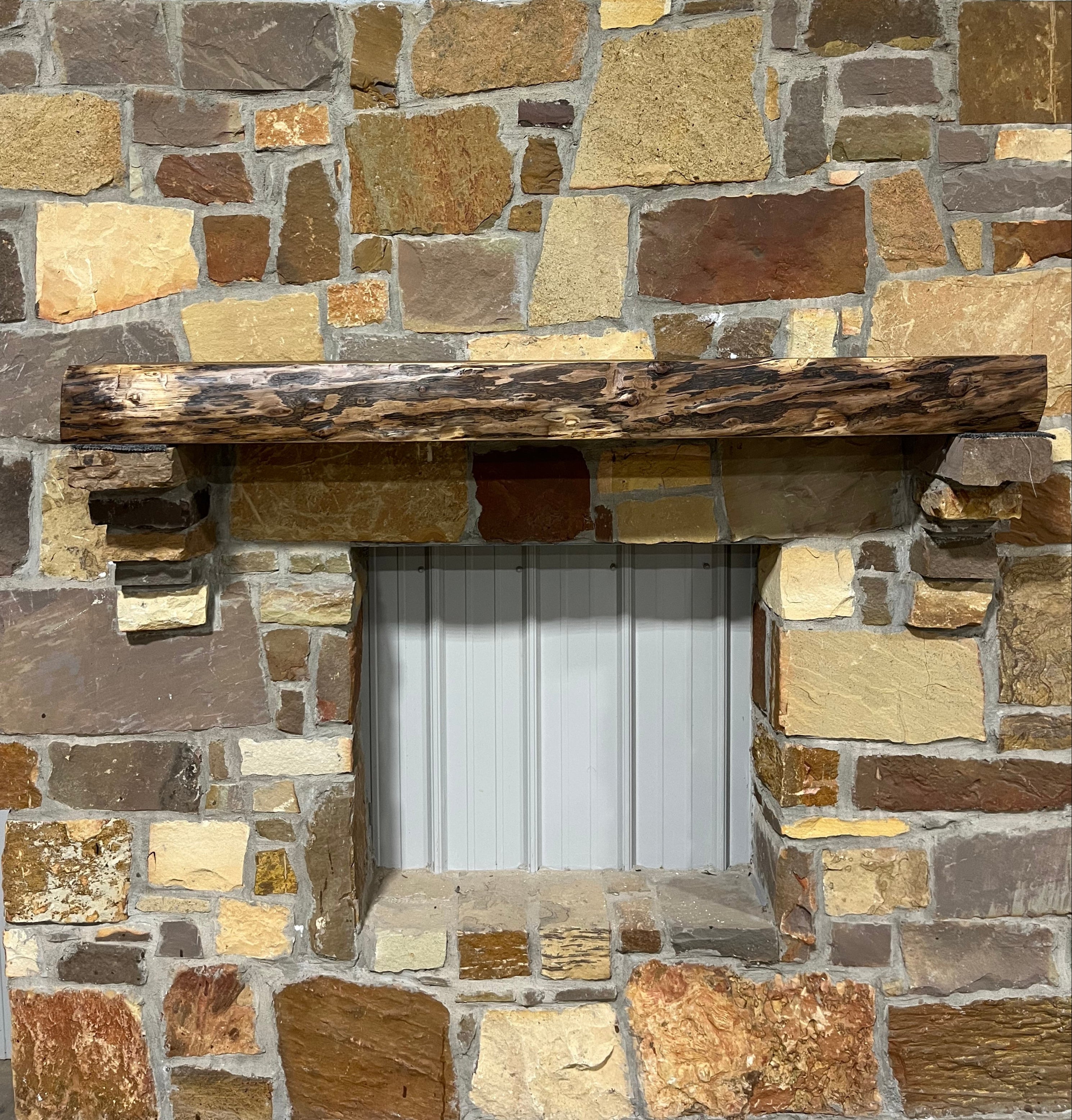 Solid live edge walnut fireplace mantel mounted on a stone wall.