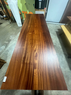 Finished Sapele wood slab with rich reddish-brown tones and ribbon-like grain pattern, displayed on concrete workshop floor.