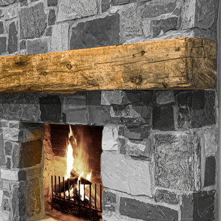 hand hewn reclaimed beam fireplace mantel mounted to stone wall
