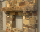 hand hewn reclaimed beam fireplace mantel mounted to stone wall
