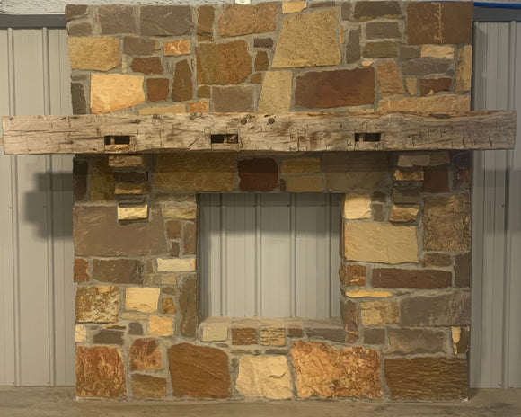 hand hewn reclaimed beam fireplace mantel mounted to stone wall
