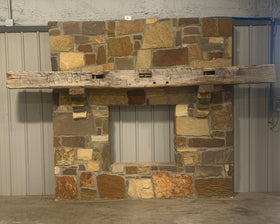hand hewn reclaimed beam fireplace mantel mounted to stone wall

